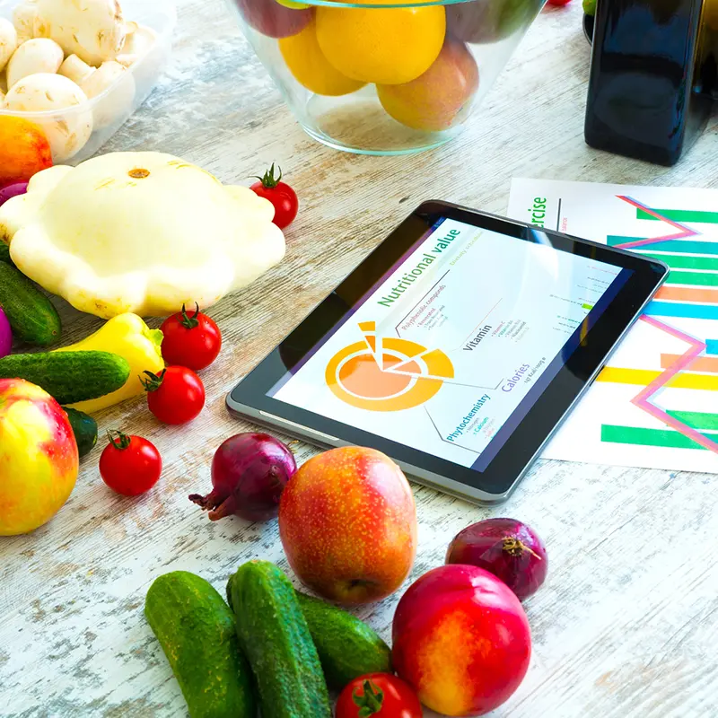 Tablet mit Ernährungschart auf Tisch mit Obst und Gemüse